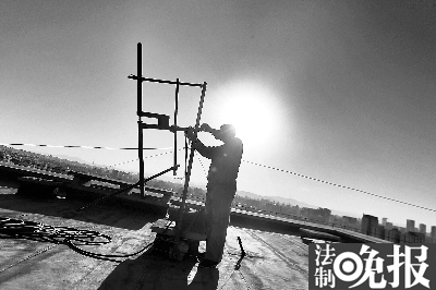 執(zhí)法人員在樓頂拆除天線  攝/記者 柴程