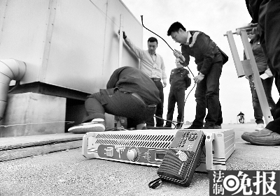 執(zhí)法人員在樓頂拆除黑電臺設備  攝/記者 柴程