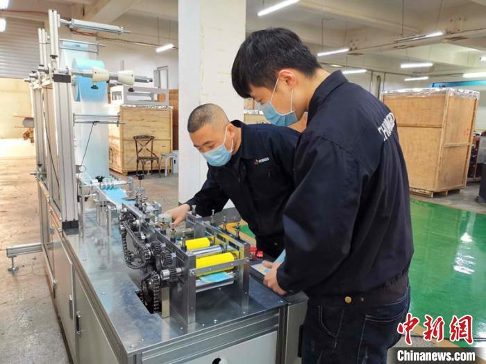 資料圖：技術(shù)工人在對(duì)口罩機(jī)生產(chǎn)線進(jìn)行最后調(diào)試。姜輝 攝